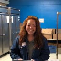 A volunteer smiles while volunteering at Kids' Food Basket.